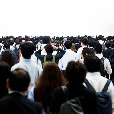 Crowd of people walking away in a busy public space.