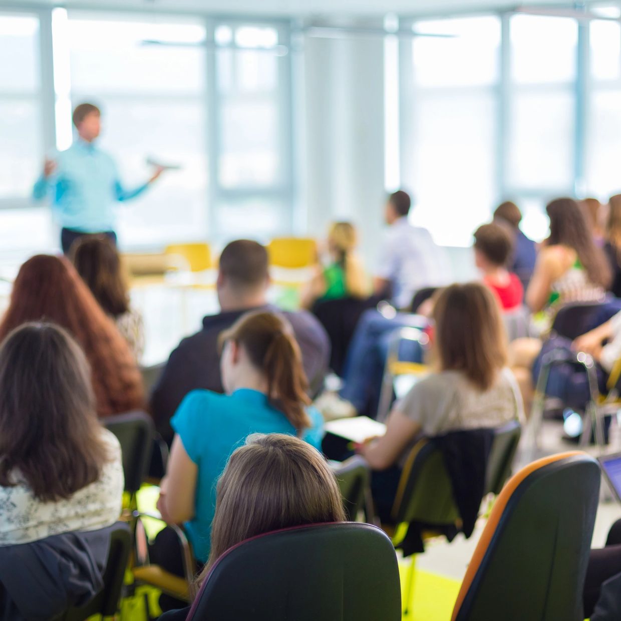 Audience attentively listening to a speaker in a bright seminar room.