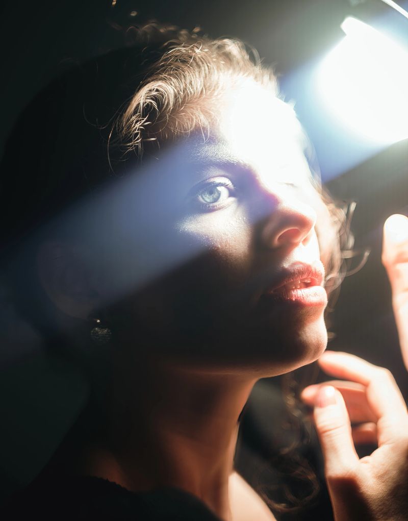 Model posing with dramatic lighting during a studio photoshoot for a beauty campaign