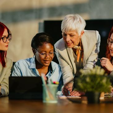Senior professional guiding diverse group of young women during a leadership strategy session