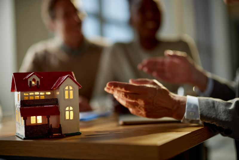 Close up of model home with real estate agent having a meeting with customers in the office.