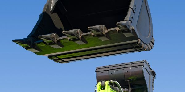 Close-up of excavator and construction machinery against blue sky.