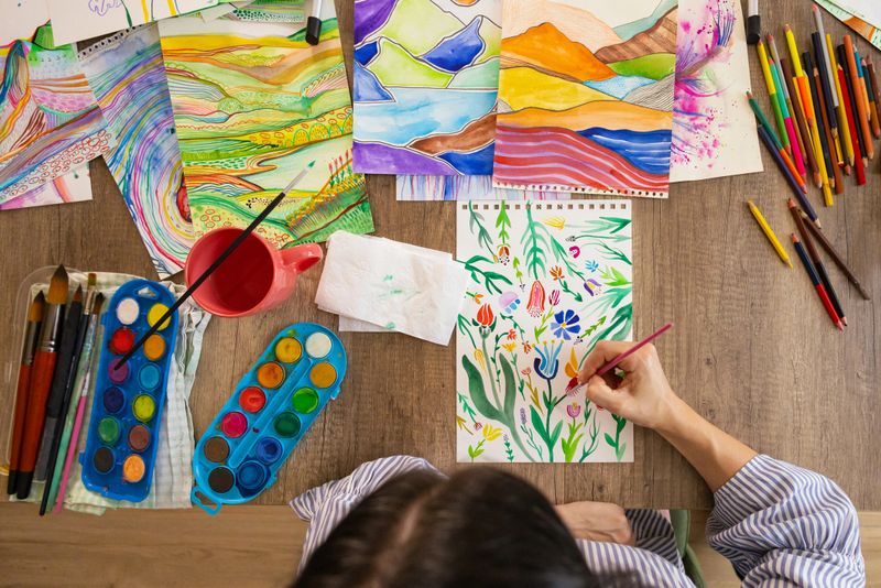 A dedicated artist uses wooden colored pencils and watercolors to draw an abstract nature scene.