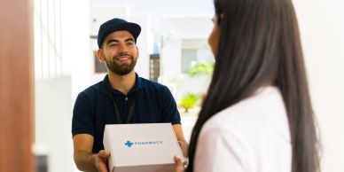 Repartidor entrega un paquete de farmacia a una mujer en la puerta.