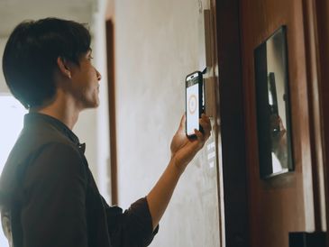 Person using smartphone to unlock a door with a digital lock.