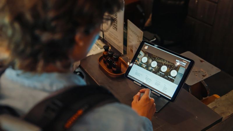 Group of friends using a self check-in kiosk at a hostel, emphasizing travel, technology, and convenience in a modern accommodation setting.