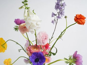 A vibrant bouquet of mixed flowers in various colors against a plain background.