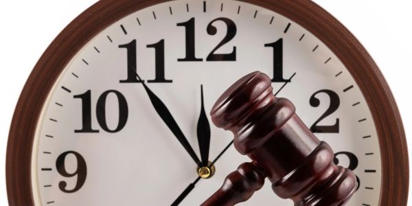 A judge's gavel in front of a clock showing 12:55.