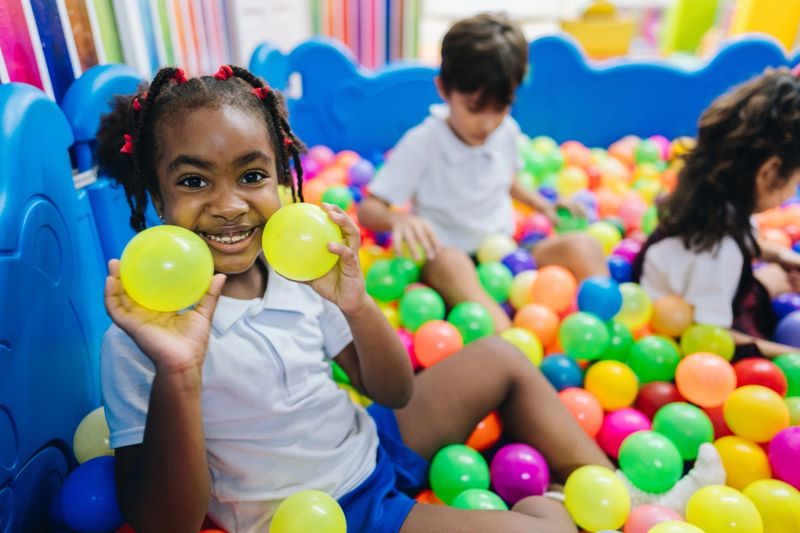 Portrait of a child girl playing on ball pool in the school playroom
