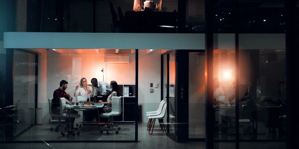 Group of people collaborating in an office meeting at night.