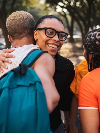 Friends happily embracing and chatting outdoors.