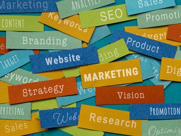 Colorful paper strips with marketing-related words scattered on a surface.