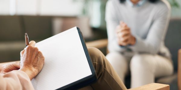 A therapist taking notes during a counseling session with a client.