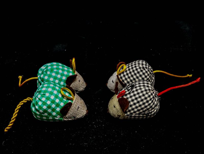 Four stuffed mice with different colors and patterns. The mice are sitting on a black background. Concept of playfulness and whimsy, as the colorful