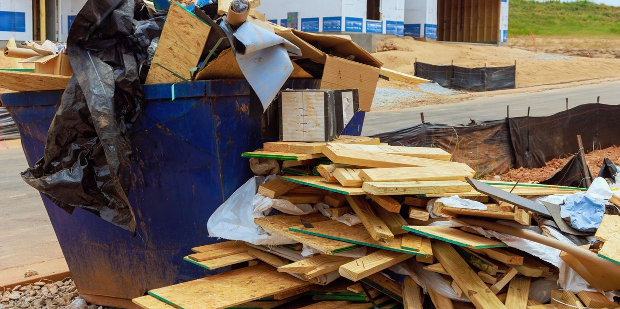 Construction waste piled in a dumpster at a housing site.
