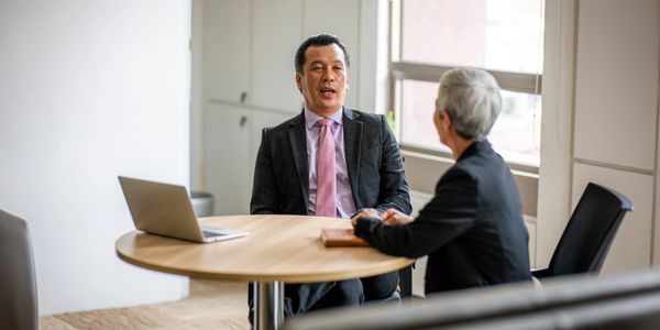 Two professionals engaged in a business discussion at a round table.