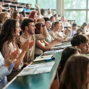 Students in a lecture hall cheering and clapping enthusiastically.