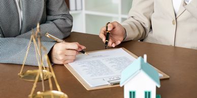 Two people reviewing and signing a document related to real estate or legal matters.