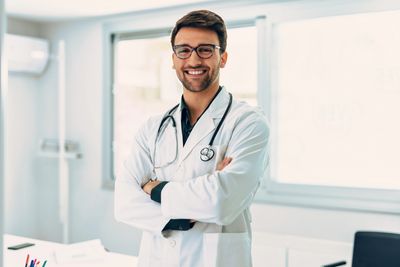 Smiling male doctor with glasses and stethoscope in a bright infusion therapy facility.