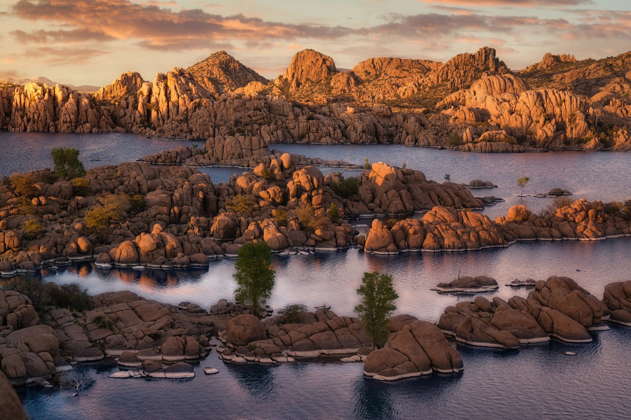 Sunset bathes rocky islands and water in warm golden hues.