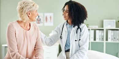 Doctor comforting a smiling elderly woman during a consultation.