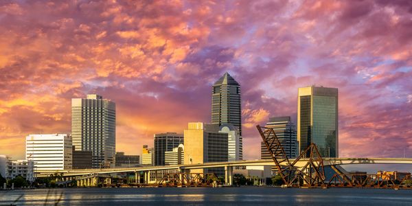 City skyline at sunset with vibrant pink and orange clouds.