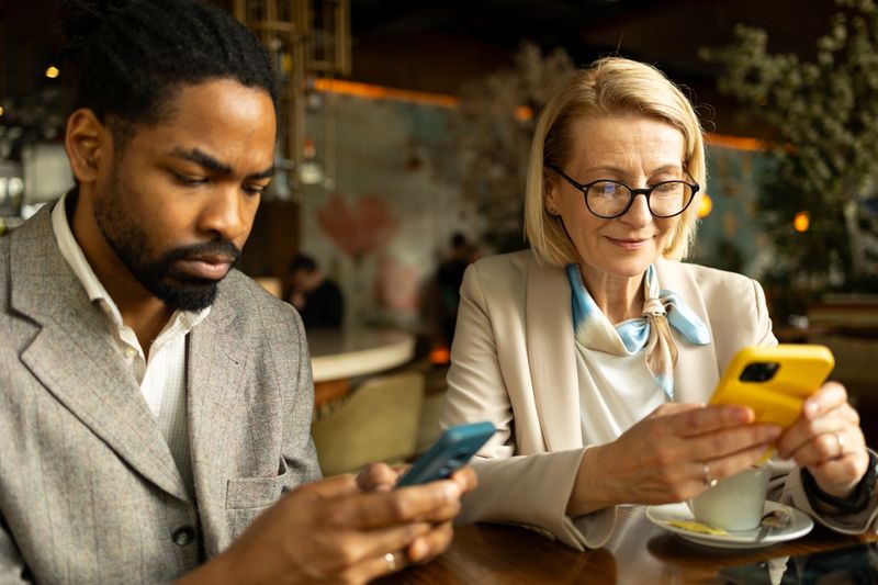 Colleagues using smartphones at a trendy coffee shop