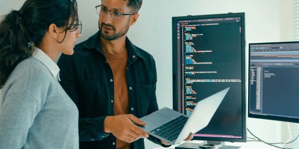 Two people discussing code on computer screens.