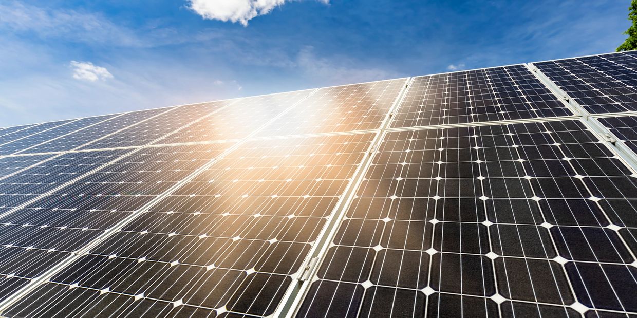 Solar panels reflecting sunlight under a bright blue sky.