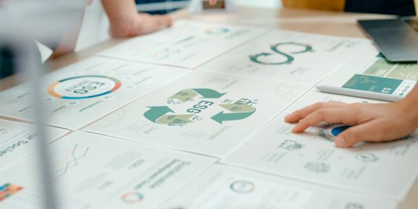 People analyzing ESG reports and charts on a table during a meeting.