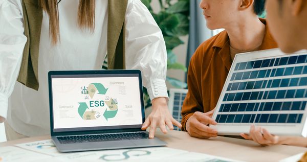 People discussing ESG concepts with a laptop and solar panel.