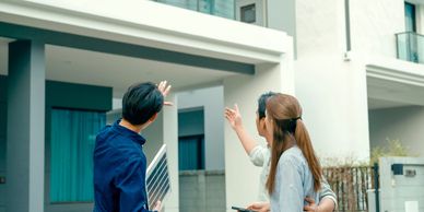 A couple discussing solar panel installation with a technician outside their modern home.