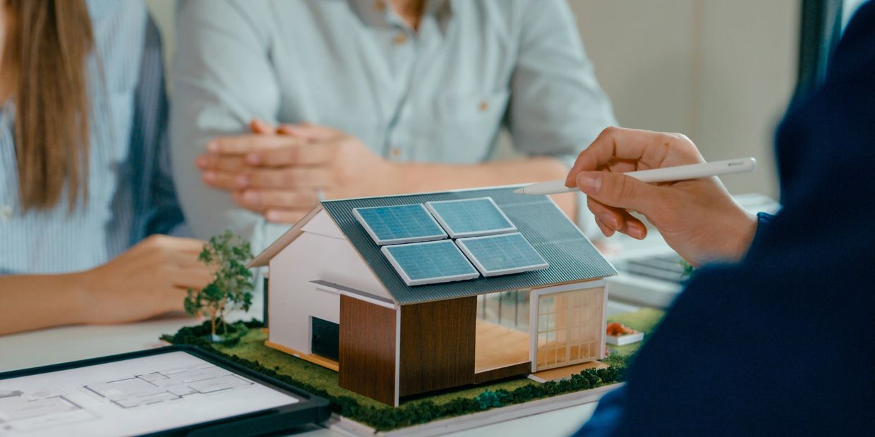 Architect discussing solar panel installation on a house model.