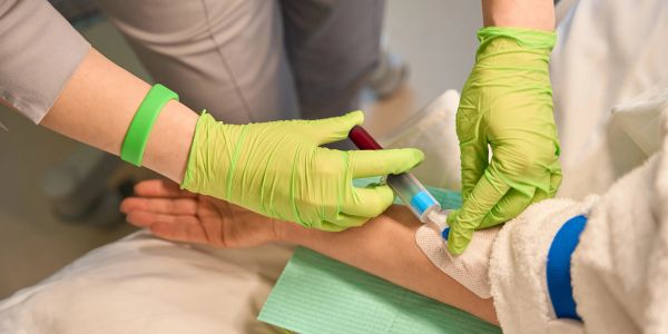 Healthcare worker drawing blood from patient's arm.