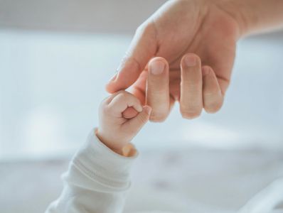 A baby's hand holding a parent's finger