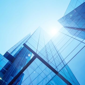 Sunlit glass skyscrapers reflect the clear blue sky in a modern cityscape.