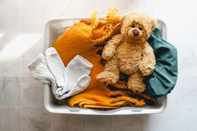 Laundry basket with a teddy bear, socks, and cozy blankets.