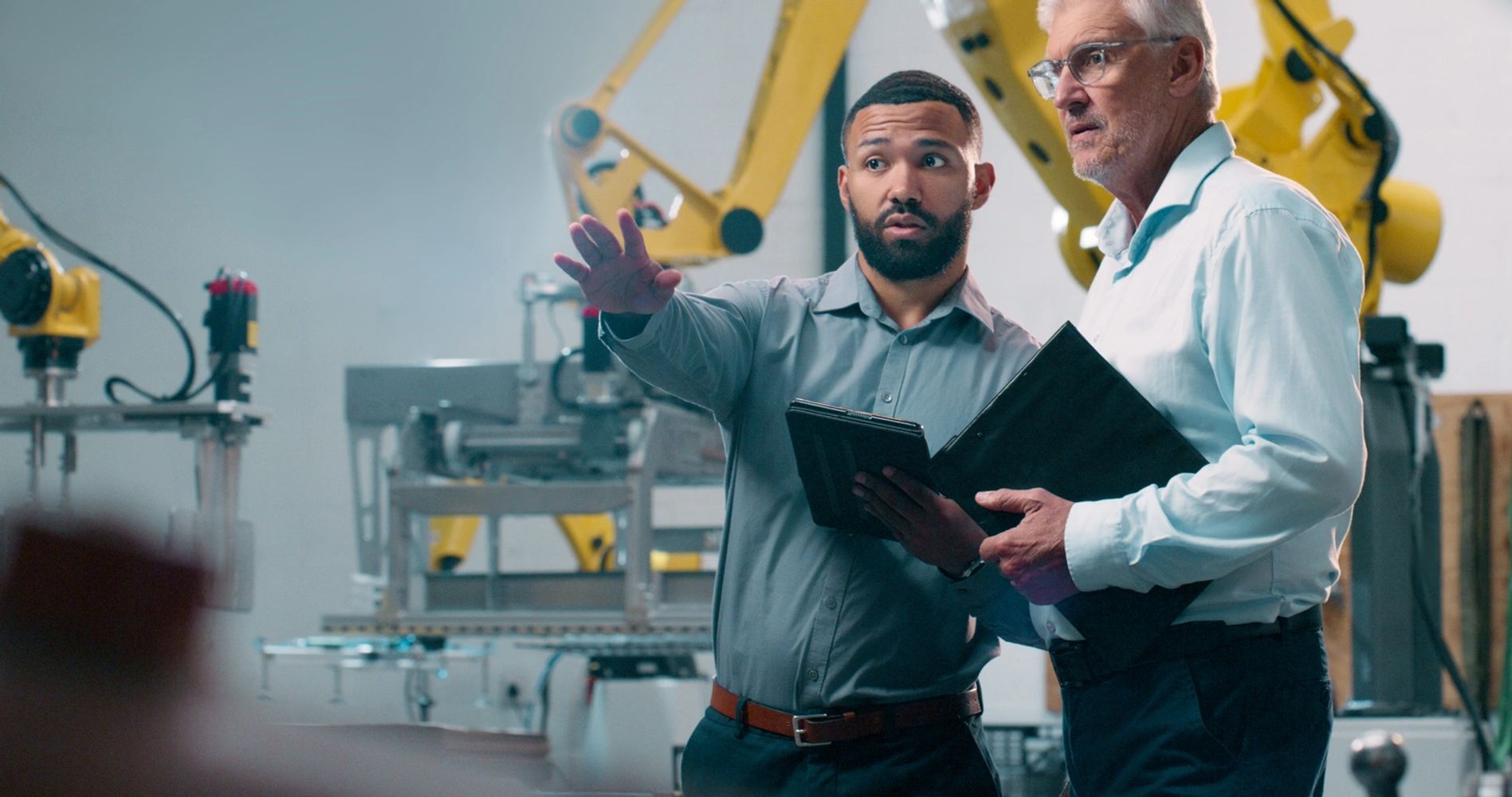 Two engineers discussing automation in a robotic manufacturing facility.