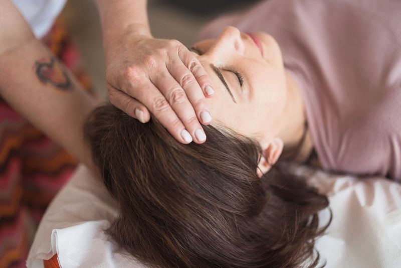 Patient having a severe headache and seeking help from a reiki therapist