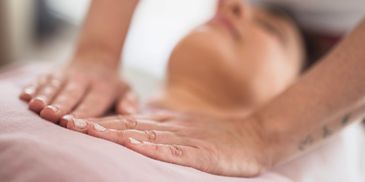 Hands gently massaging a person's chest during a therapy session.