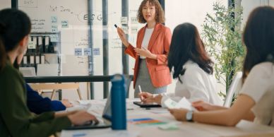 Woman presenting to colleagues in a meeting room.