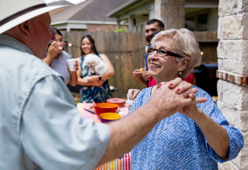 Mexican senior couple dancing together at a family party outdoors and looking very happy