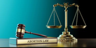 Gavel and scales of justice next to an abortion law book.