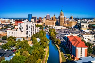 City skyline with river and buildings under a clear blue sky.