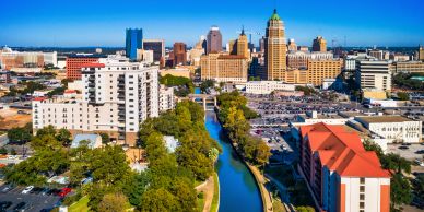 City skyline with river and buildings under clear blue sky.