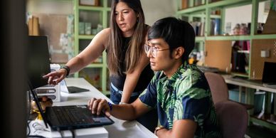  man is operating a computer and a woman is pointing at the computer screen