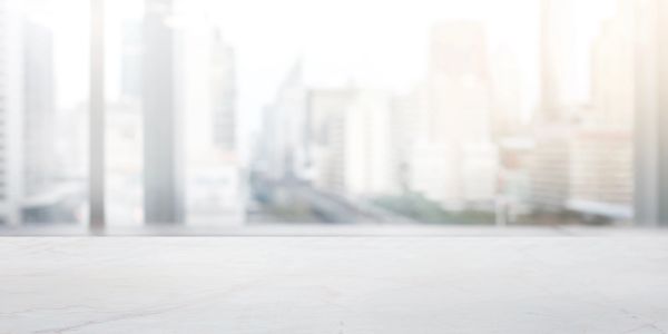 Empty white marble table with blurred city background.