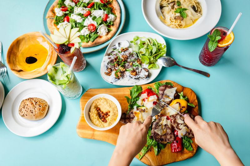 Female hand cutting steak on the table. Shot from directly above