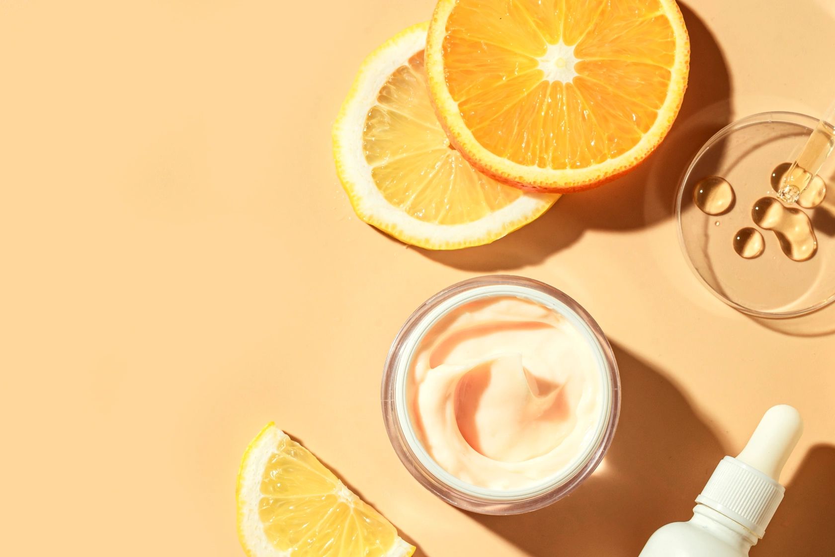 Skincare products with citrus slices on a peach background.