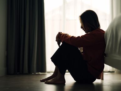Silhouetted woman sitting on floor in contemplation.